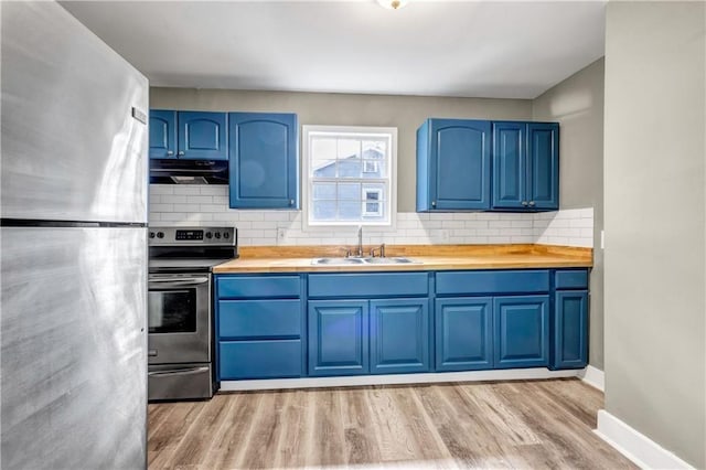 kitchen with blue cabinetry, stainless steel appliances, under cabinet range hood, and a sink