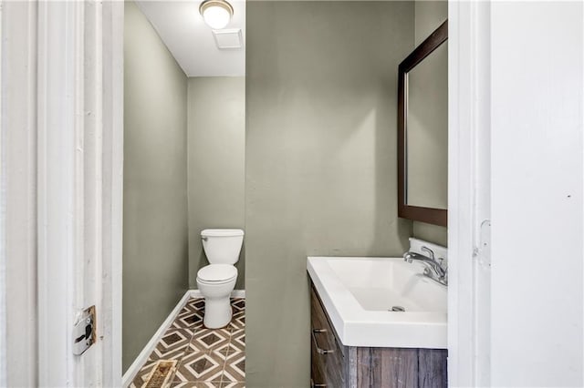 half bathroom featuring toilet, vanity, and baseboards