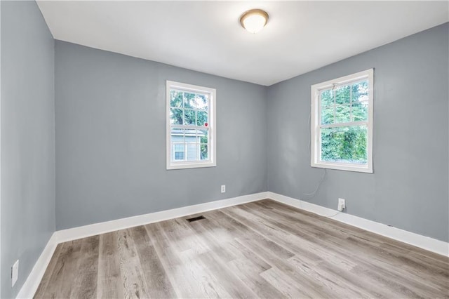 unfurnished room with visible vents, baseboards, and wood finished floors