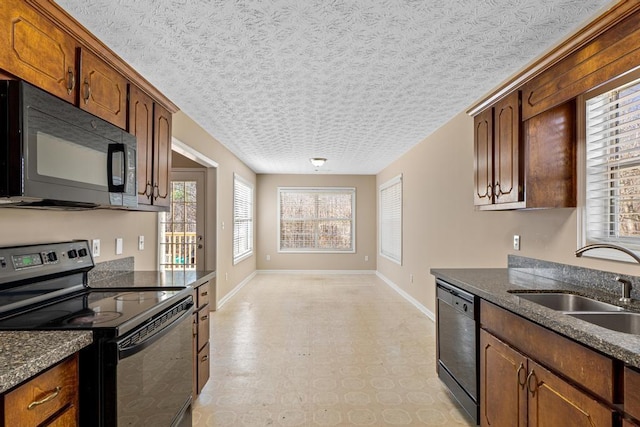 kitchen with sink, dark stone counters, a textured ceiling, and black appliances