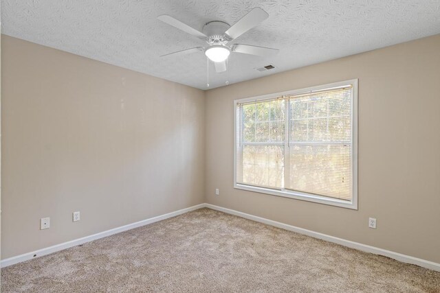 carpeted spare room featuring ceiling fan and a textured ceiling