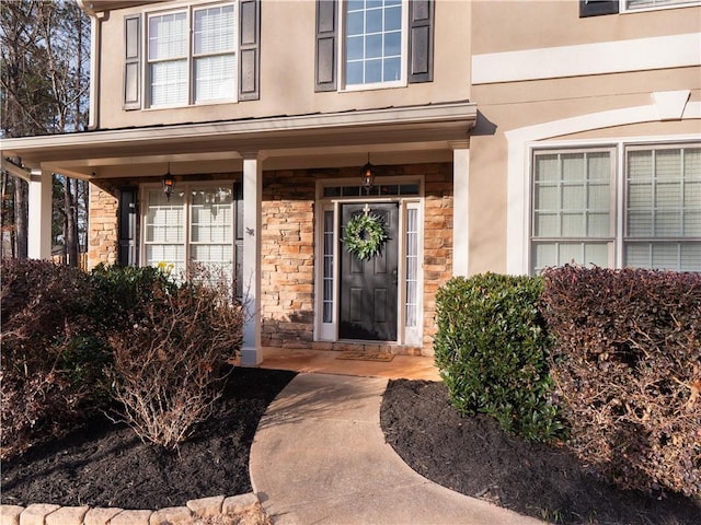 view of exterior entry featuring stone siding and stucco siding