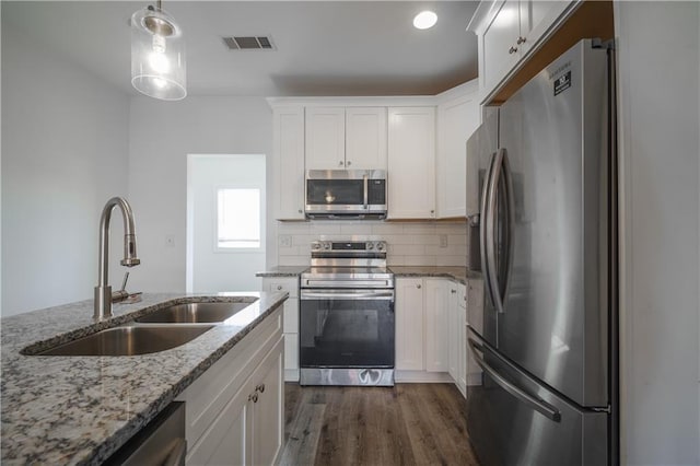 kitchen with sink, white cabinets, hanging light fixtures, light stone counters, and stainless steel appliances