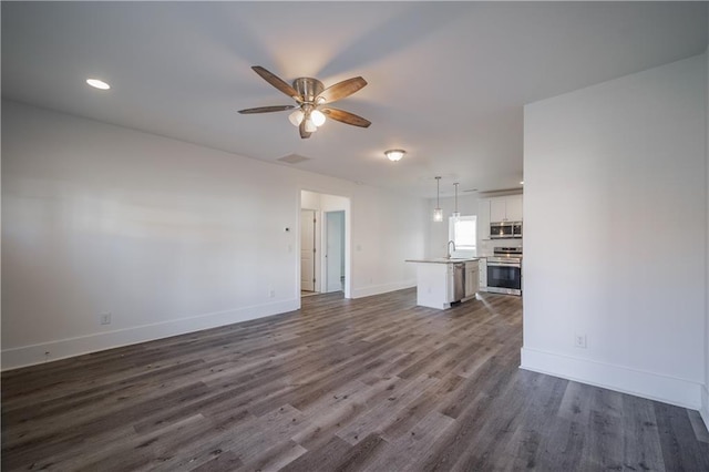 unfurnished living room with sink, dark hardwood / wood-style floors, and ceiling fan