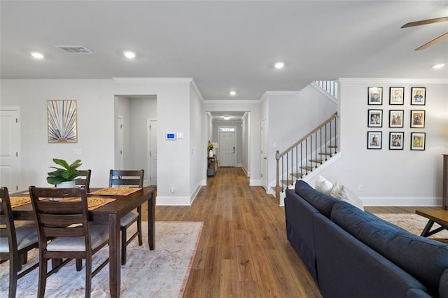 dining room featuring visible vents, ceiling fan, baseboards, stairs, and wood finished floors