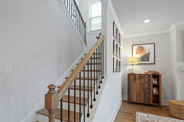 stairway with baseboards, wood finished floors, and crown molding