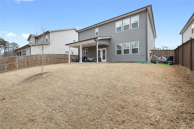 back of house featuring a trampoline and a fenced backyard