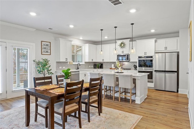 dining space with plenty of natural light, visible vents, and light wood-type flooring