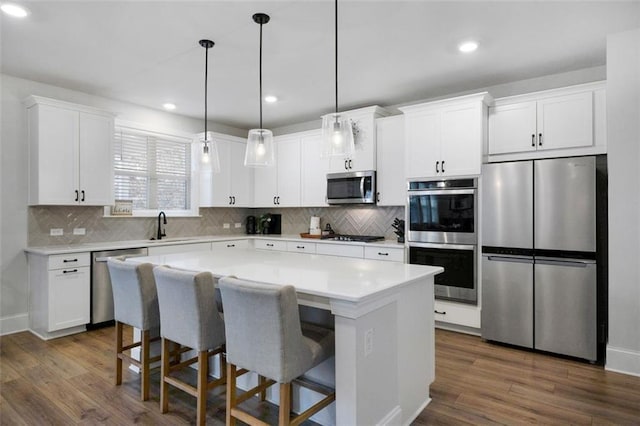 kitchen with a kitchen island, light countertops, dark wood-style floors, white cabinets, and stainless steel appliances