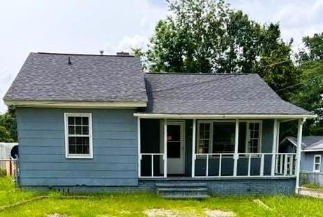 rear view of house with a porch and a lawn