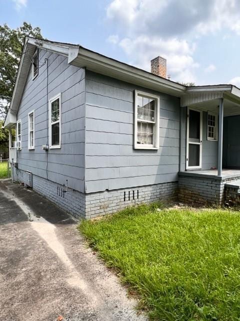 view of property exterior with crawl space, covered porch, and a chimney