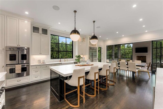 3773 Randall Rd SE, Atlanta, GA 30339 - kitchen with stainless steel double oven, crown molding, white cabinets, a sink, and a kitchen island