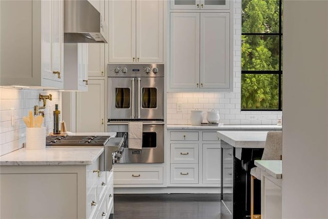 3773 Randall Rd SE, Atlanta, GA 30339 - kitchen featuring stainless steel appliances, backsplash, ventilation hood, light stone counters, and white cabinets