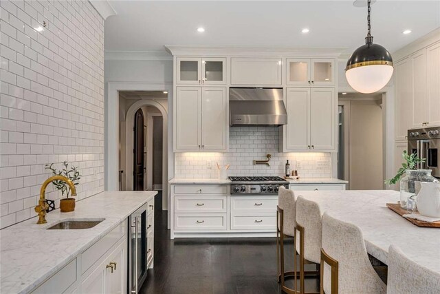 3773 Randall Rd SE, Atlanta, GA 30339 - kitchen featuring wall chimney exhaust hood, stainless steel appliances, backsplash, wine cooler, and crown molding