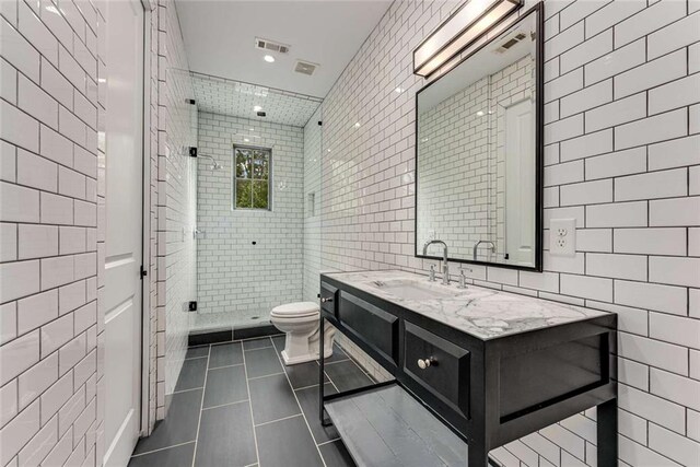 3773 Randall Rd SE, Atlanta, GA 30339 - bathroom featuring tile walls, tile patterned flooring, a stall shower, toilet, and vanity