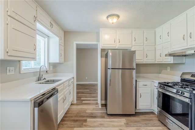 270 Hunt Ridge Dr, Stockbridge, GA 30281 - kitchen featuring stainless steel appliances, under cabinet range hood, a sink, light wood-type flooring, and white cabinetry