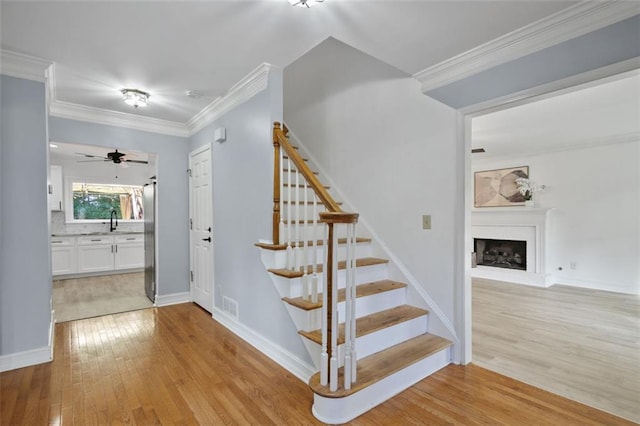 2316 Fripp Overlook NW, Acworth, GA 30101 - stairway with wood finished floors, a fireplace with raised hearth, ceiling fan, and ornamental molding