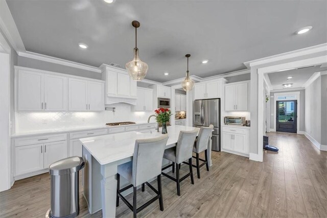 kitchen with white cabinetry, appliances with stainless steel finishes, decorative light fixtures, and a breakfast bar area