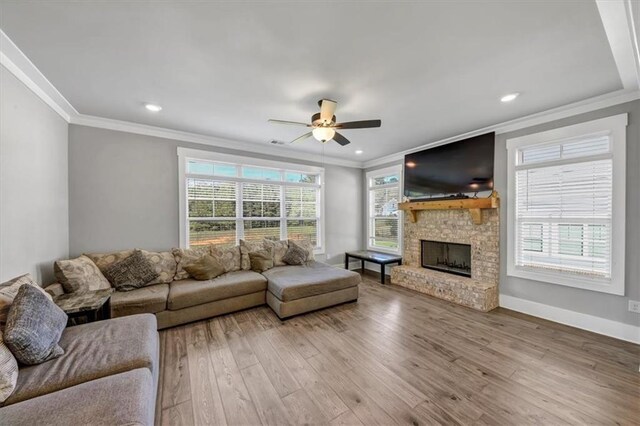 living room with crown molding, a brick fireplace, and light hardwood / wood-style floors