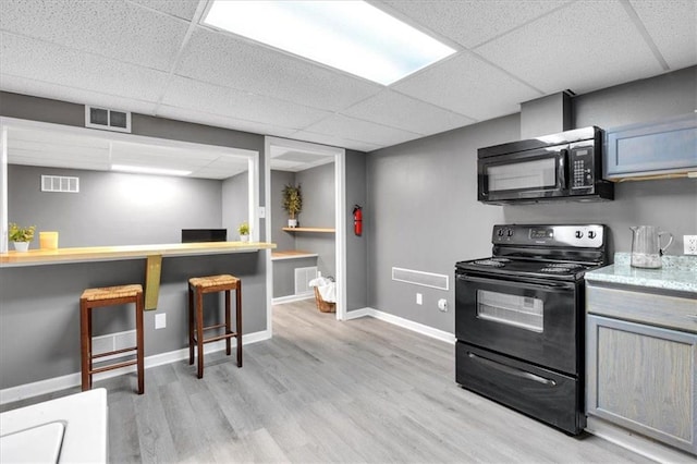 kitchen with black appliances, a paneled ceiling, light wood finished floors, baseboards, and gray cabinetry
