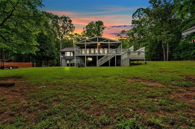 back of house featuring stairs, a deck, and a lawn