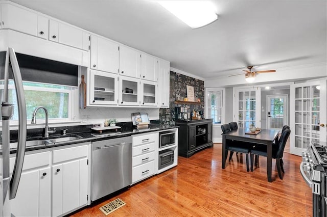 kitchen featuring appliances with stainless steel finishes, dark countertops, ceiling fan, white cabinetry, and light wood-style flooring