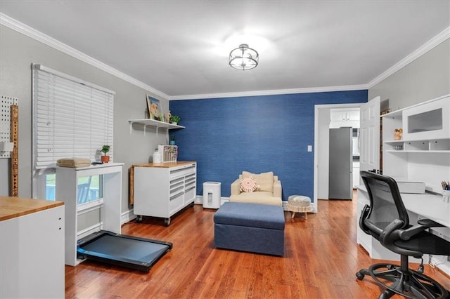 office space featuring an accent wall, wood finished floors, crown molding, and baseboards