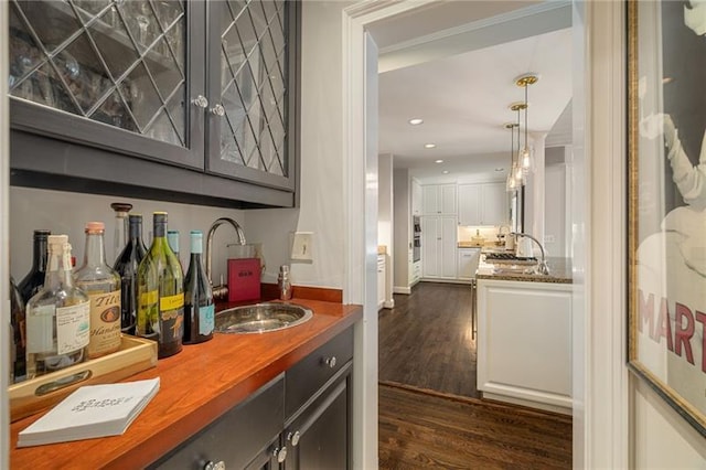 bar with dark wood-style floors, recessed lighting, a sink, indoor wet bar, and pendant lighting