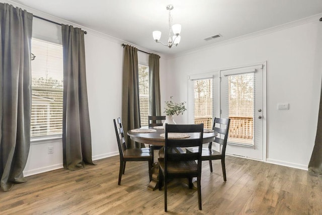 dining area with an inviting chandelier, wood-type flooring, ornamental molding, and plenty of natural light