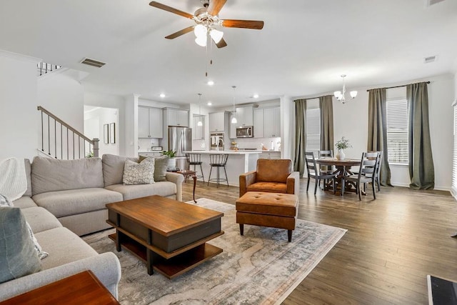 living room with dark hardwood / wood-style floors and ceiling fan with notable chandelier