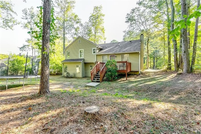 rear view of property featuring a trampoline and a deck