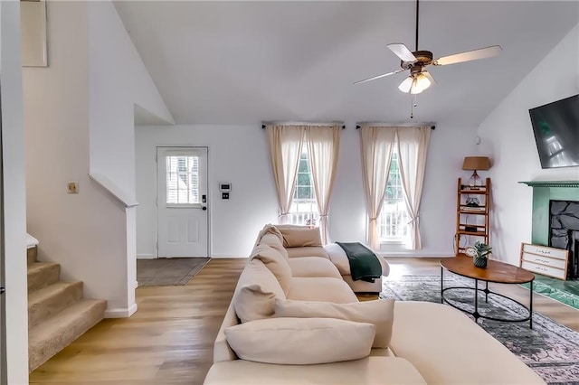 living room with light hardwood / wood-style floors, lofted ceiling, and ceiling fan