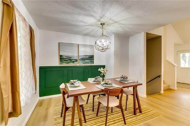 dining area featuring a chandelier, a textured ceiling, and light hardwood / wood-style floors