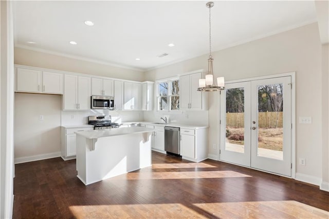 5997 Creek Indian Dr, Sugar Hill, GA 30518 - kitchen featuring appliances with stainless steel finishes, white cabinetry, crown molding, light countertops, and a center island