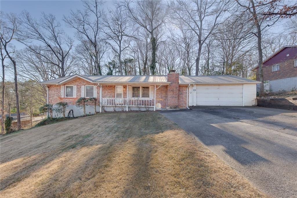 single story home featuring a front yard, a garage, and a porch