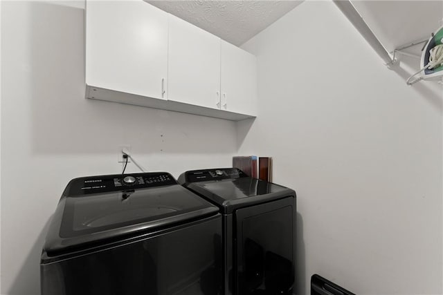 laundry room with cabinet space, washer and dryer, and a textured ceiling