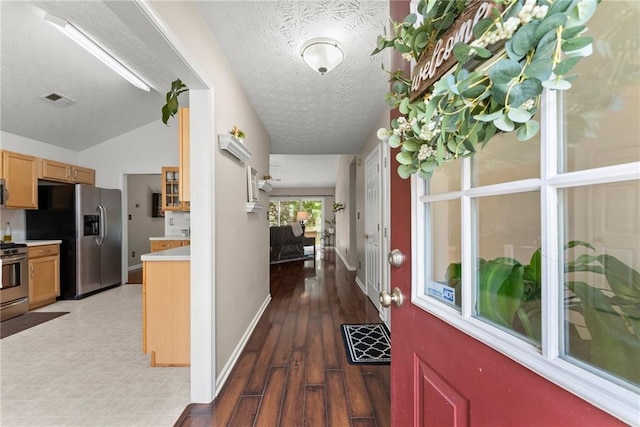 corridor with visible vents, baseboards, vaulted ceiling, wood finished floors, and a textured ceiling