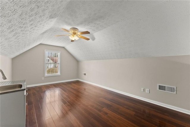 bonus room with visible vents, dark wood-type flooring, baseboards, ceiling fan, and a sink