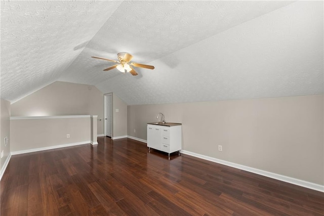 bonus room with a ceiling fan, wood finished floors, baseboards, lofted ceiling, and a textured ceiling