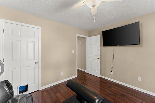 workout room with ceiling fan, baseboards, a textured ceiling, and wood finished floors