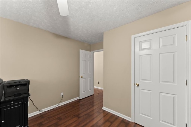 bedroom with ceiling fan, a textured ceiling, dark wood-type flooring, and baseboards