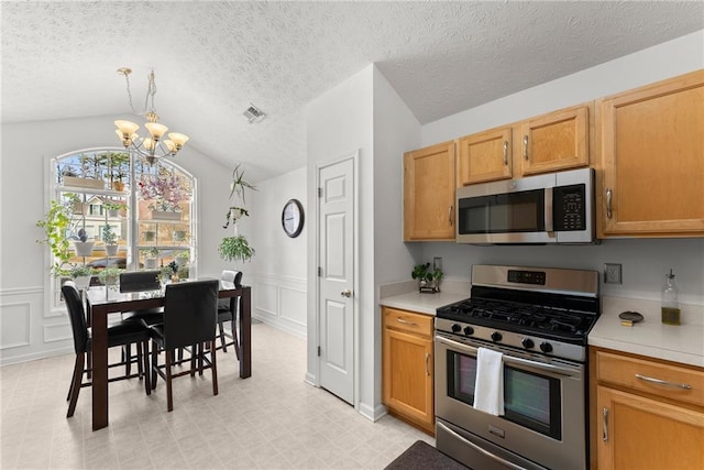 kitchen featuring visible vents, stainless steel appliances, an inviting chandelier, light countertops, and vaulted ceiling