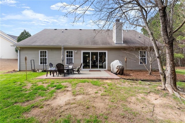 rear view of property featuring a patio area, a lawn, and a chimney