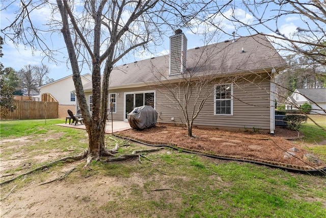 rear view of house featuring a patio area, a chimney, a yard, and fence