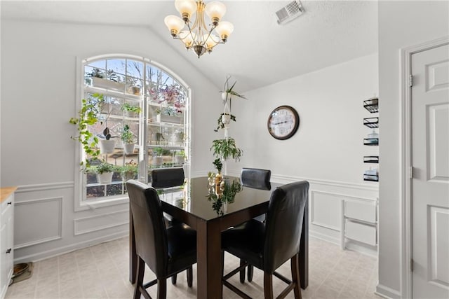 dining space featuring visible vents, an inviting chandelier, a wainscoted wall, and vaulted ceiling