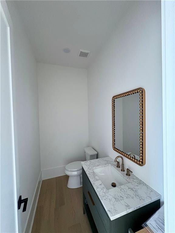 bathroom with wood finished floors, toilet, vanity, and baseboards