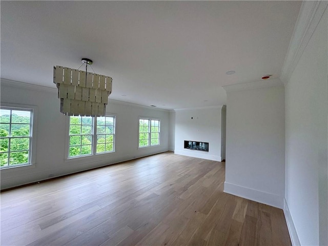 unfurnished living room with ornamental molding, wood finished floors, and baseboards