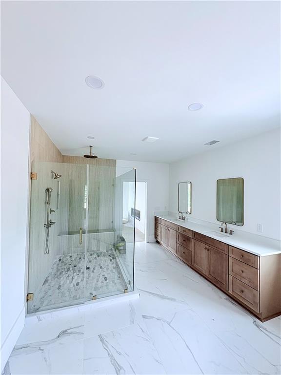 bathroom with a stall shower, double vanity, marble finish floors, and recessed lighting