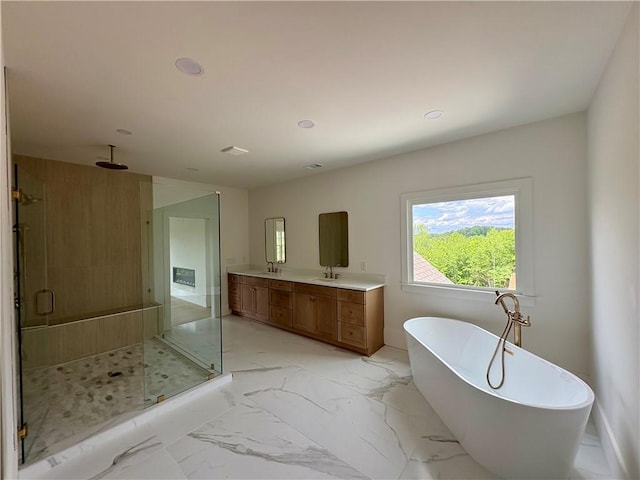 bathroom featuring a stall shower, a soaking tub, double vanity, recessed lighting, and baseboards