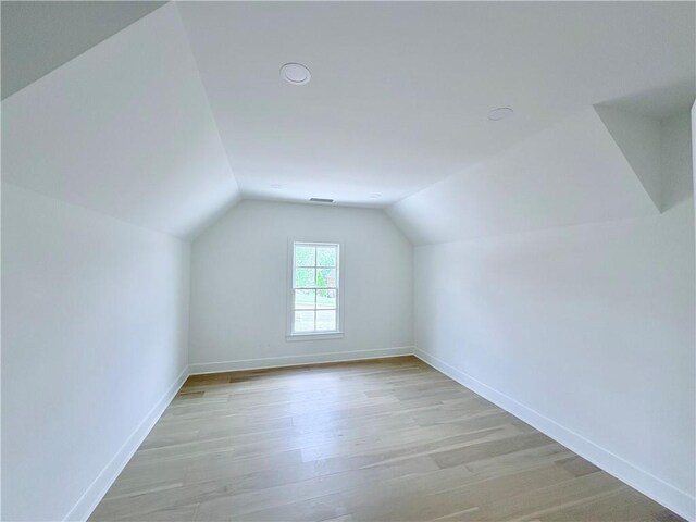 bonus room featuring lofted ceiling, baseboards, and light wood-style flooring
